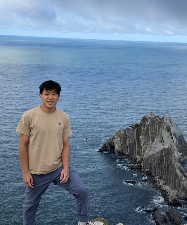 Jeremy smiling on a clifftop above the sea